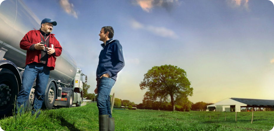 Two men smiling and talking while standing near a dairy truck in the early morning